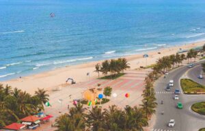 sea with a beach and a road with electric vehicles, looking for charging locations on the go in Europe.